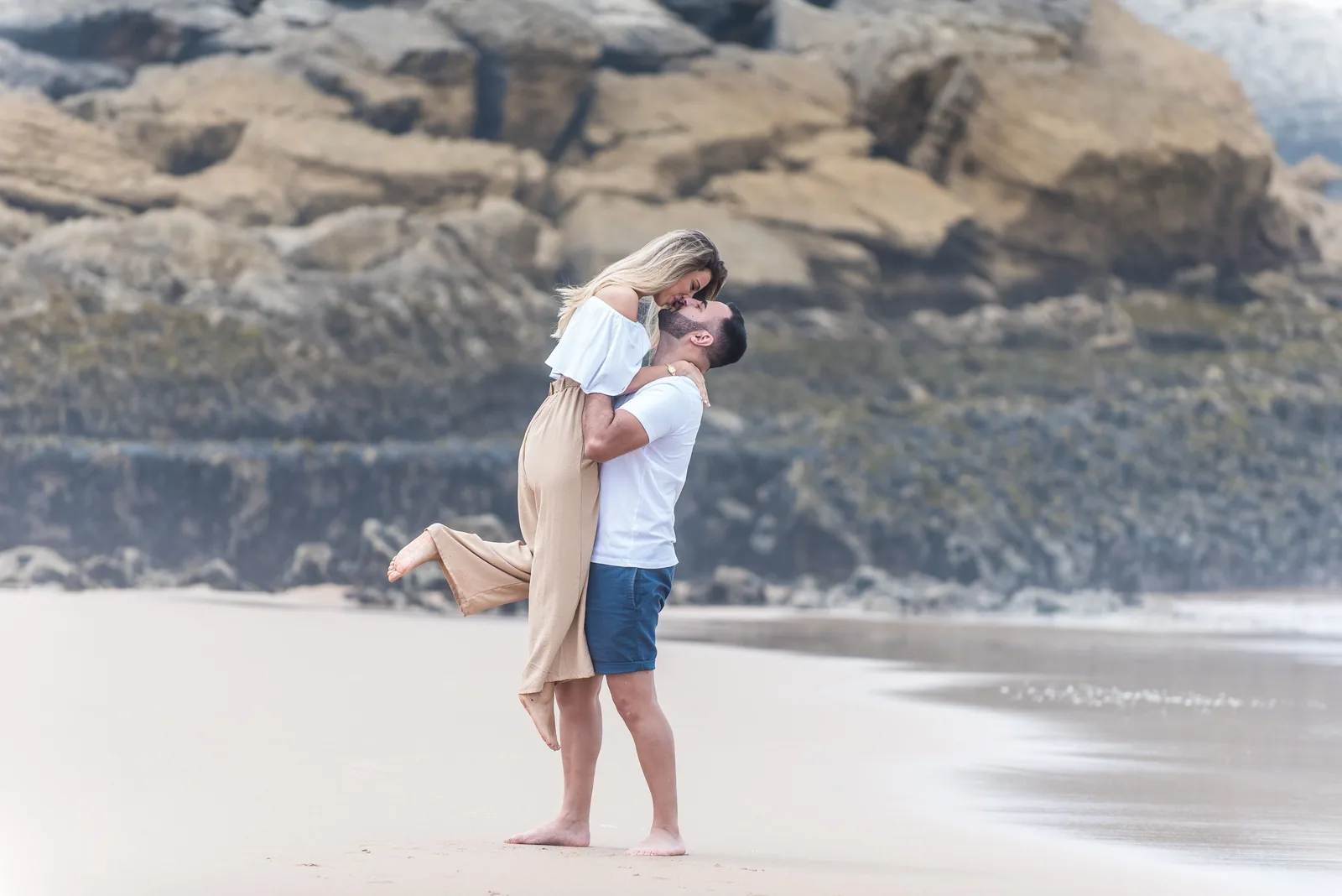 Casal abraçado na praia, entre as rochas