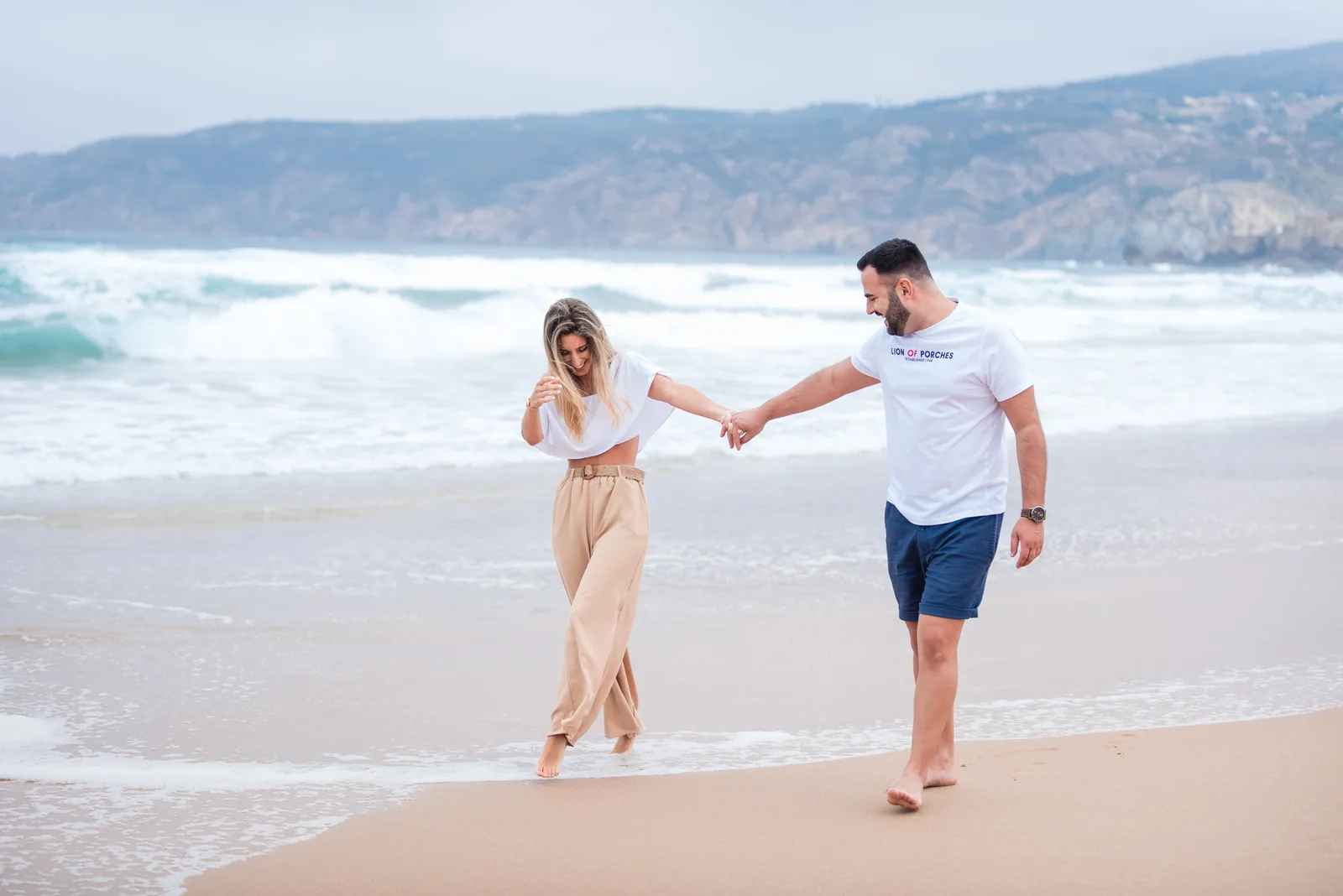 Casal de mãos dadas a caminhar à beira-mar